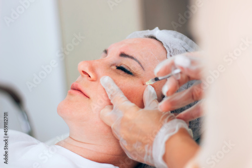 Botox injection into mimic wrinkles by a cosmetologist in a cosmetology office.
