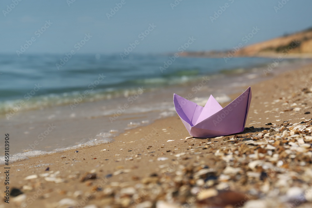 Paper boat on sandy beach near sea, space for text Paper boat on sandy beach near sea, space for text