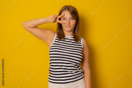 Young woman in striped shirt making victory, positive, peace sign on her eye