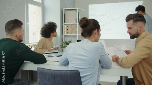 Group of young people in smart casual wear analyzing data on projection screen