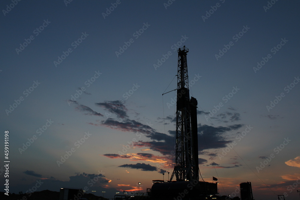 Obraz premium Drilling rig towering over the West Texas landscape at dusk, excellent screensaver or desktop photo.
