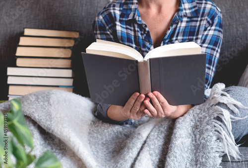 Woman sitting on couch reading book 