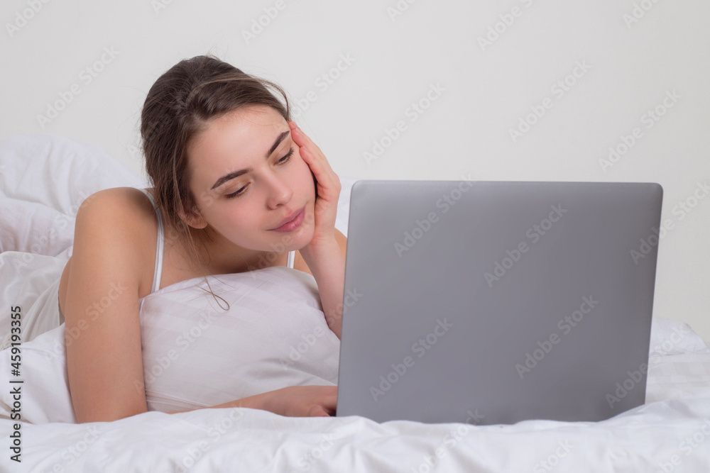 Young beautiful woman lying for relaxing and enjoying with notebook on bed in the white bedroom at home. Young beautiful woman lying for relaxing and enjoying with notebook on bed in the white bedroom at home.