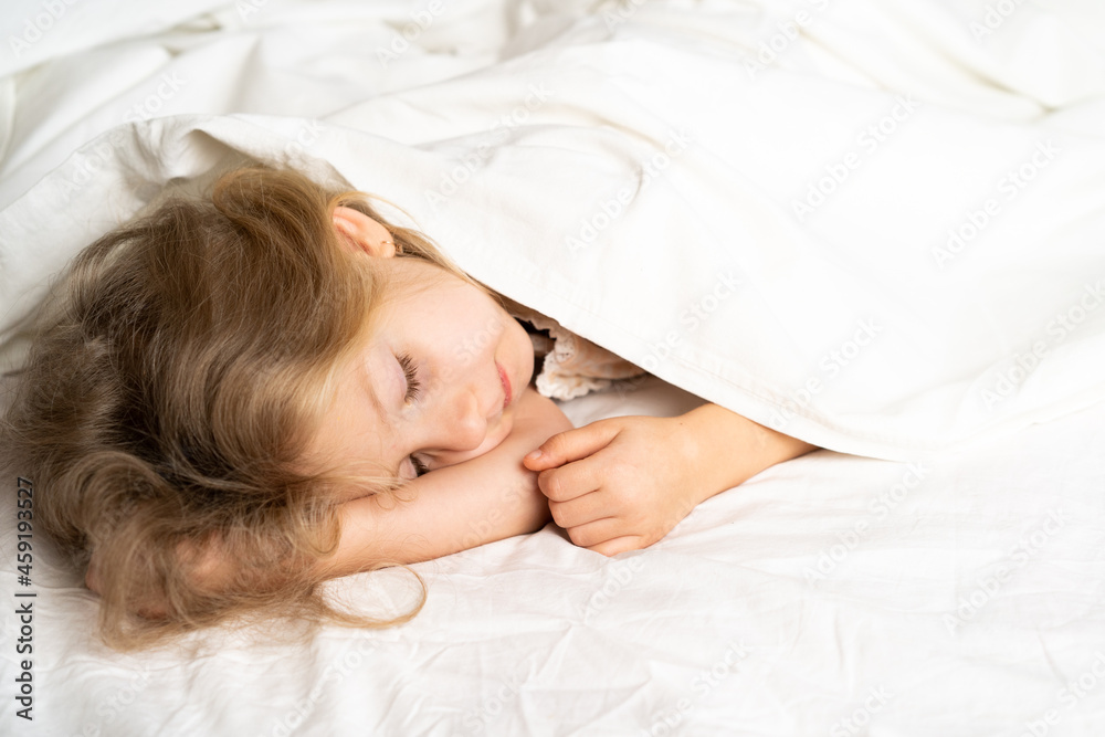 A little blonde is sleeping sweetly in a bed with white underwear. space for the text. healthy sleep of the child A little blonde is sleeping sweetly in a bed with white underwear. space for the text. healthy sleep of the child