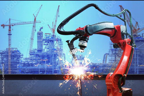 Industrial robot welder welding i beam steel structure construction by metal arc welding against industrial factory site in sunset