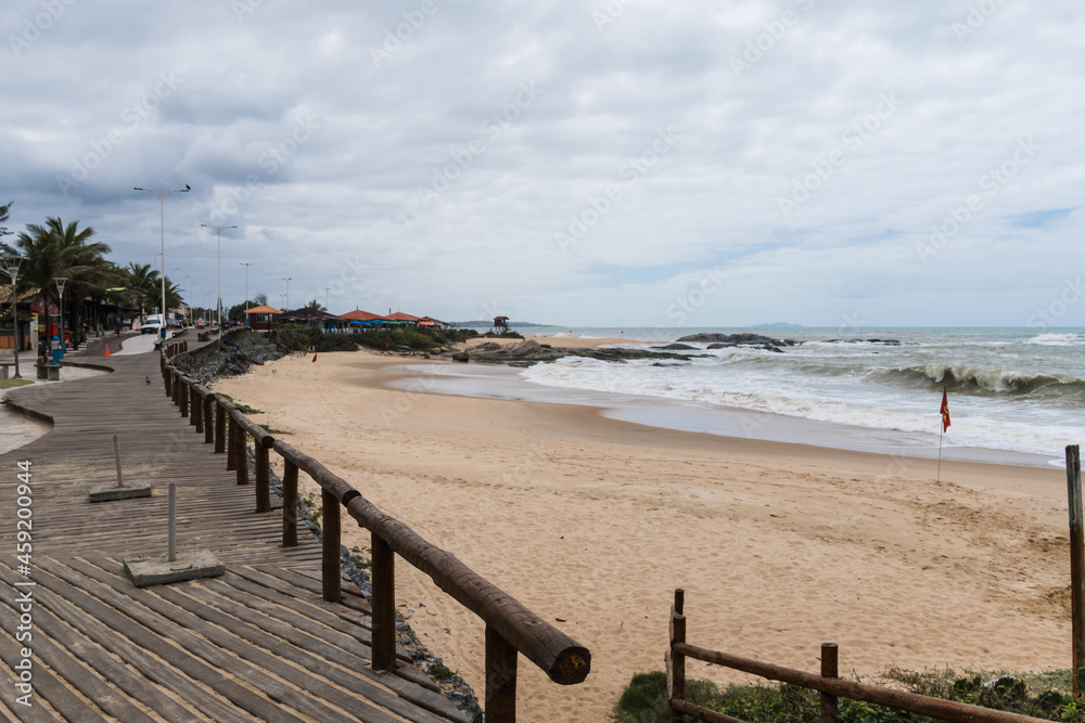 View of the beach of Rio das Ostras in Rio de Janeiro with cloudy sky and some heavy clouds. Strong sea and yellowish sand.
