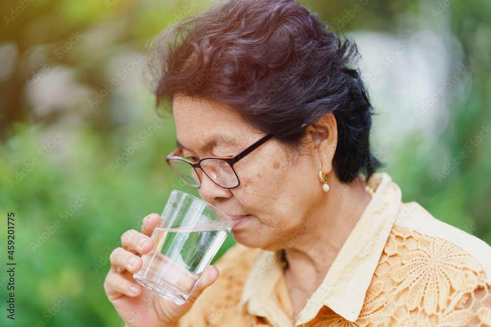Old woman drinking from a glass of water. Health care concept. Old woman drinking from a glass of water. Health care concept.