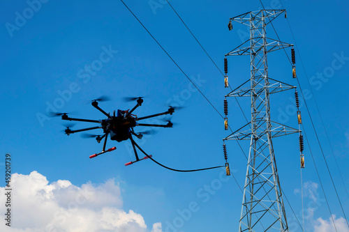 Drone stringing transmission lines of electrical high power. stringing via our method reduces cost and risk for electric utilities.
