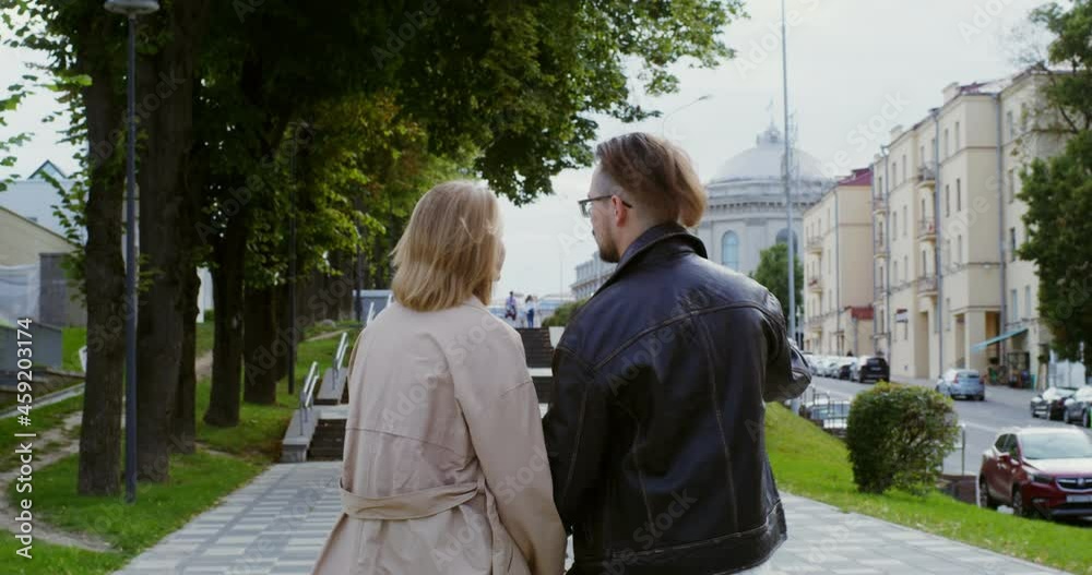 Stylish guy and girl are walking around the city, holding hands and talking Stylish guy and girl are walking around the city, holding hands and talking