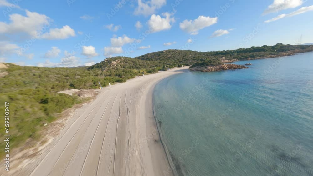 FPV video, view from above, aerial view from an FPV drone flying at high speed over a green coast with a beautiful white sand beach bathed by a turquoise water. Prince Beach (Spiaggia del Principe) FPV video, view from above, aerial view from an FPV drone flying at high speed over a green coast with a beautiful white sand beach bathed by a turquoise water. Prince Beach (Spiaggia del Principe)