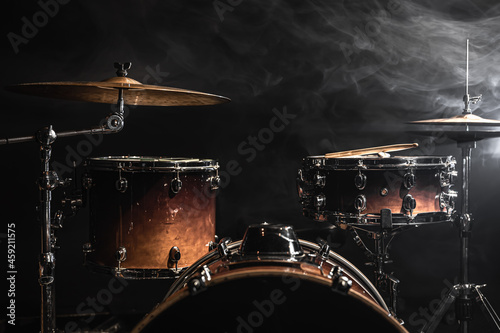Drum kit on a dark background with stage lighting, copy space.