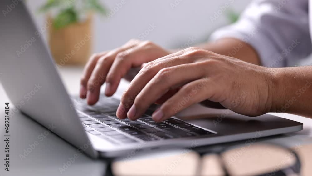 Close-up of man hands typing on laptop keyboard on white table at home office or workplace. 