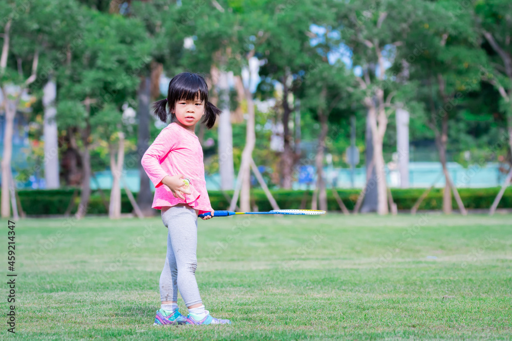 Child playing sports are wondering and looking at something. Cute girl holds a badminton racket and a badminton ball in her hand. Child playing sports are wondering and looking at something. Cute girl holds a badminton racket and a badminton ball in her hand.
