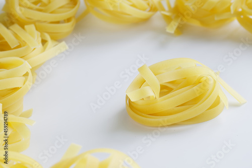 Durum wheat fettuccine pasta lies on a white surface. Cooking food. Light background. Daylight