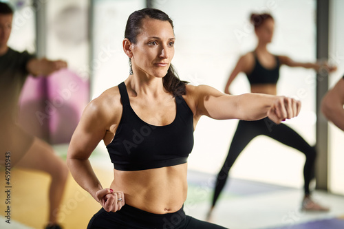 Athletic woman in fighting stance exercises hand punches during martial arts training at health club.