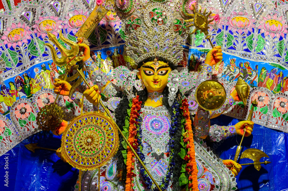 Fototapeta premium Beautiful face of Goddess Durga idol with her full glory, Durga Puja festival at night. Shot under colored light at Howrah, West Bengal, India.