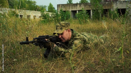 soldier in camouflage take aim with a rifle in a prone position photo