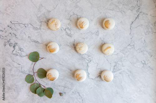 Tasty macarons on color background. Vanilla macarons with gilding on a marble table