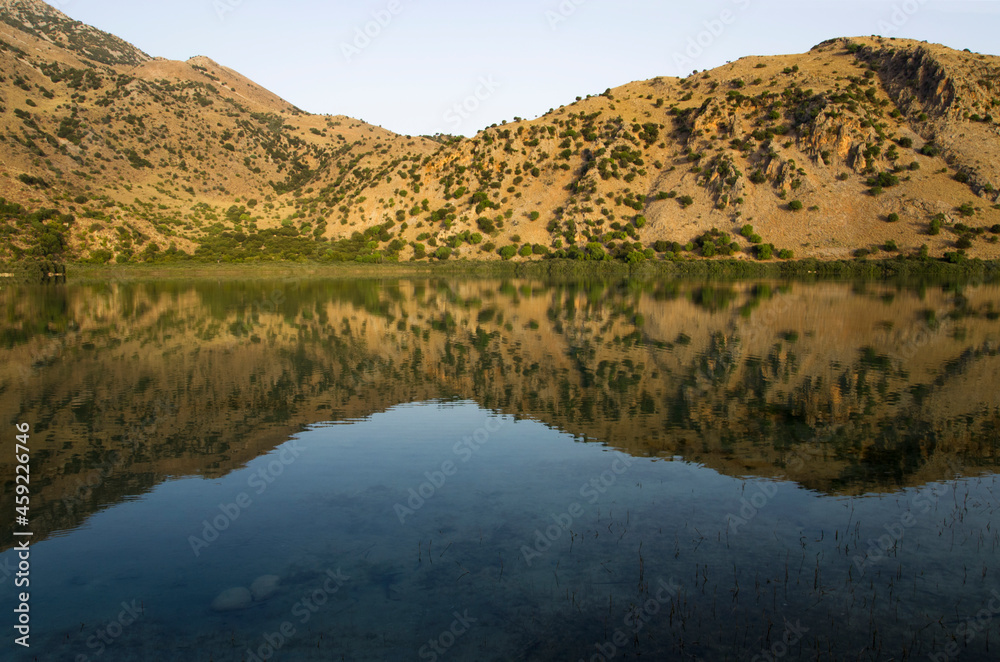 Mountain lake landscape with reflection in water at sunrise