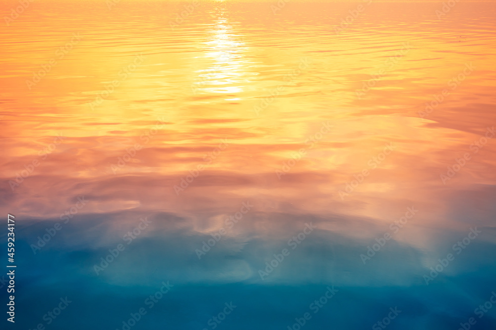 Seascape at sunset light. Calm sea water with clouds and sun reflection. Abstract nature landscape background