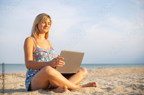 Beautiful young woman working with laptop on the tropical beach. Successful person concept