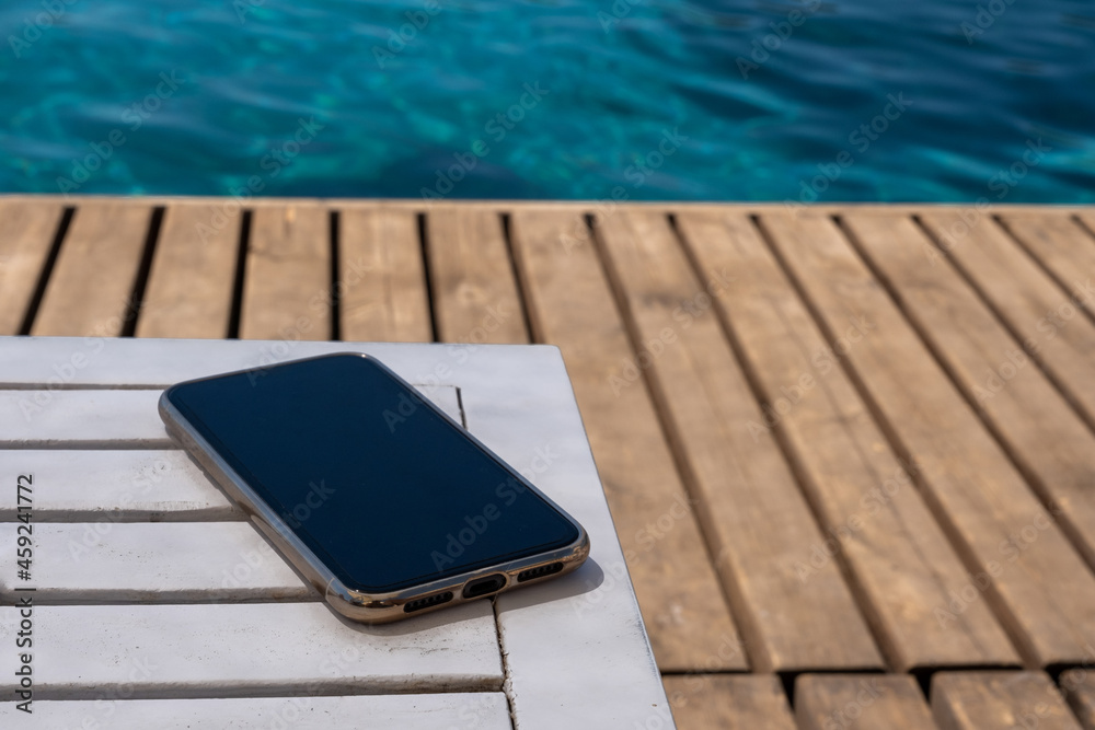 mobile phone standing on wooden floor by the beach