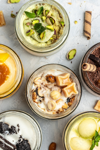 Set ice cream served in a glass jar, italian dessert gelato pistachio, chocolate, caramel, melon, mango, oreo cookies, vertical image. top view