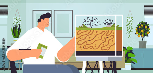 young man taking care of ant farm guy feeding ants in formicarium domestic insects concept living room interior