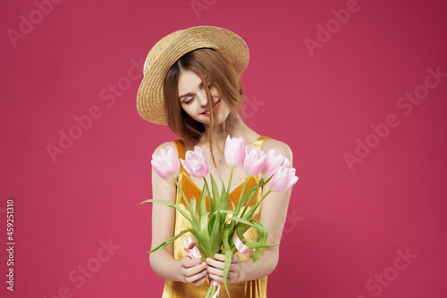 pretty woman in dress with bouquet of flowers pink background