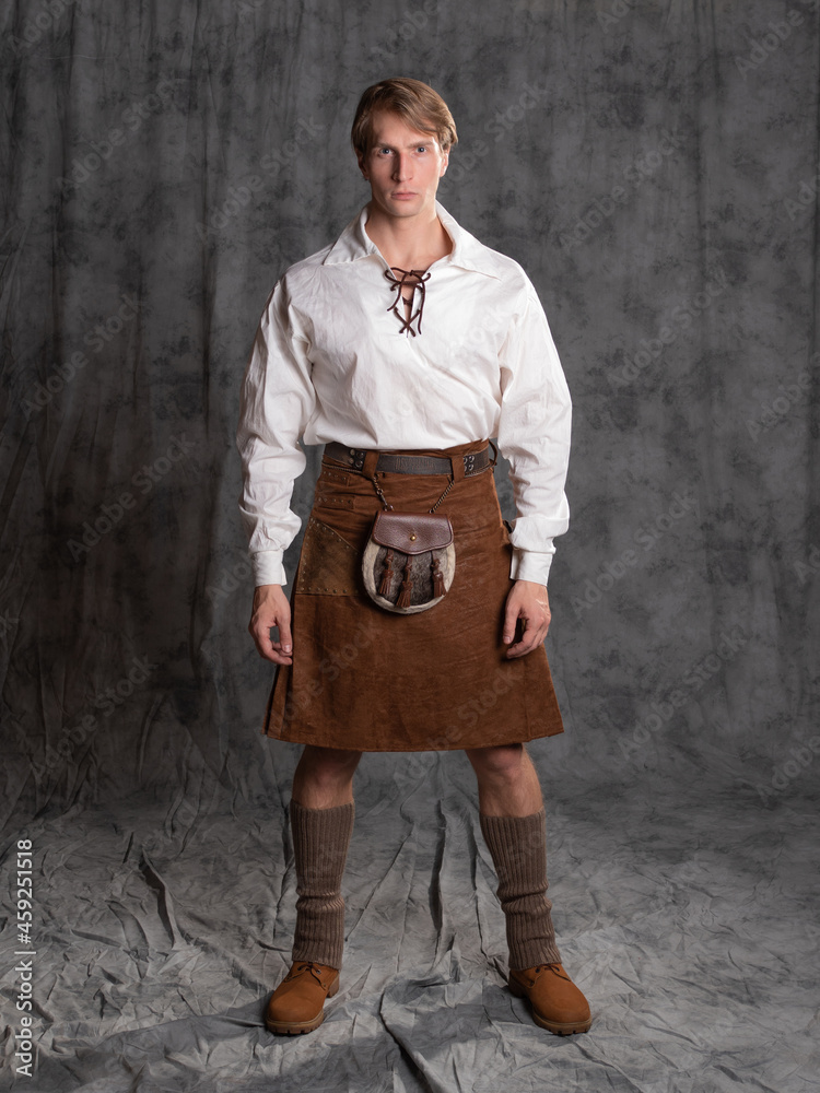 A young man in a leather kilt and a white lace-up blouse. A Scottish knight - obrazy, fototapety, plakaty 