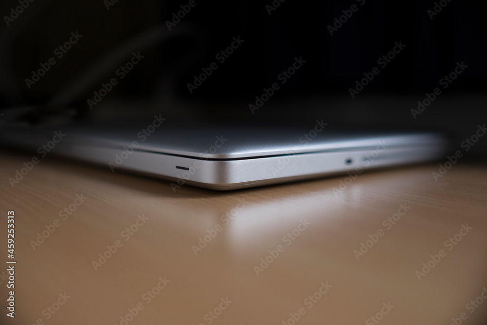 Closed aluminum laptop on a shiny wooden table. It is reflected in the table. Background photo, copy space Closed aluminum laptop on a shiny wooden table. It is reflected in the table. Background photo, copy space