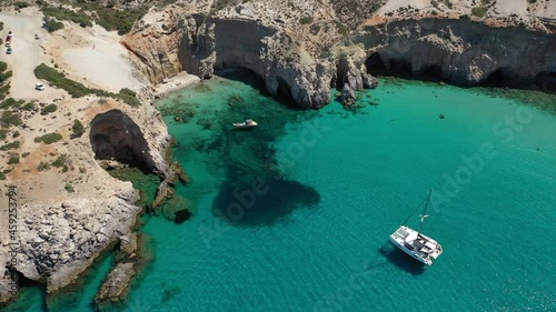 Aerial drone video of beautiful scenic rocky cove and beach of Tsigrado with caves and crystal clear emerald sea, Milos island, Cyclades, Greece photo