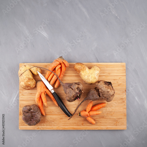 Different Ugly vegetables (potato; carrot; beetroot) on cutting board, top view. Concept - Food organic waste reduction. Using in cooking imperfect products