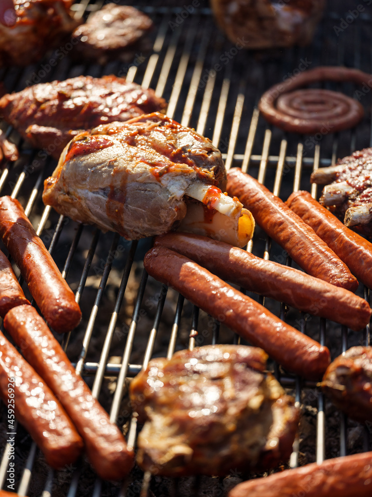 Cooking and roasting pork, beef, chicken meat and sausages on the grill. Picnic with barbecue on the outdoor nature background Cooking and roasting pork, beef, chicken meat and sausages on the grill. Picnic with barbecue on the outdoor nature background
