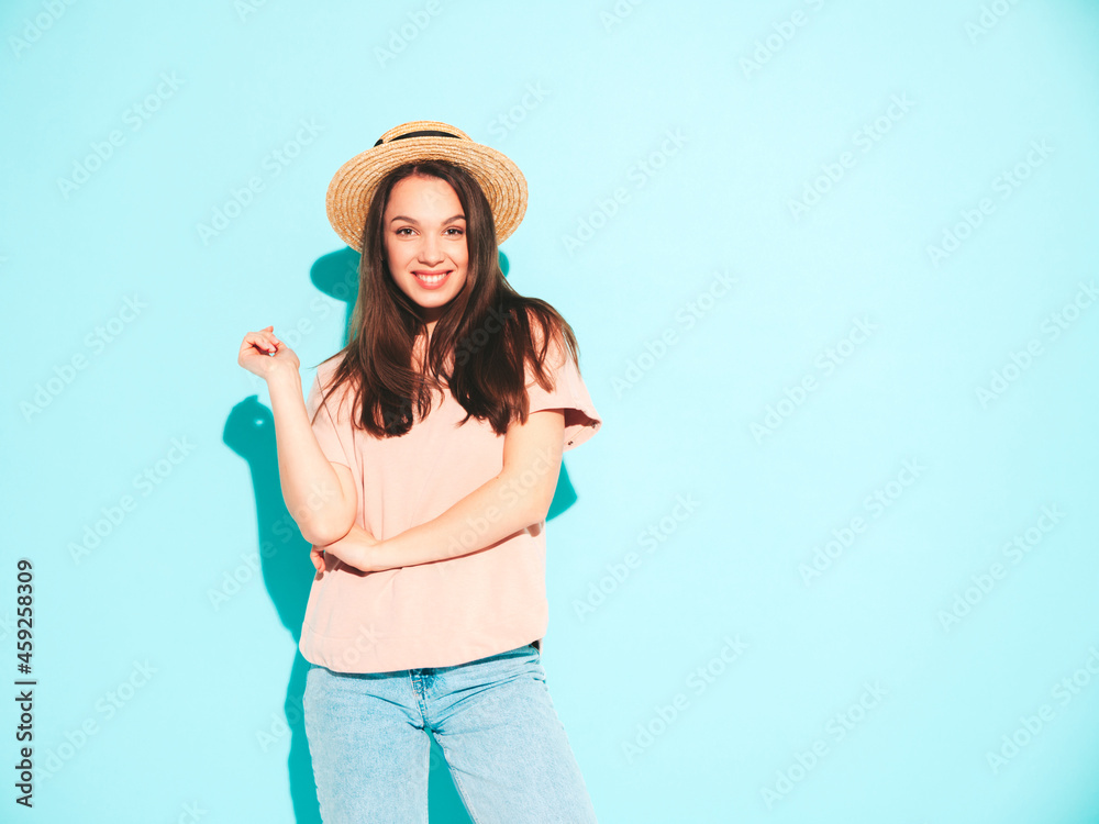 Portrait of young beautiful smiling female in trendy summer hipster clothes. Sexy carefree woman posing near blue wall in studio. Positive model having fun in hat. Cheerful and happy Portrait of young beautiful smiling female in trendy summer hipster clothes. Sexy carefree woman posing near blue wall in studio. Positive model having fun in hat. Cheerful and happy
