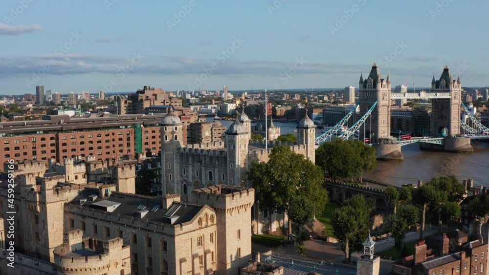 Backwards reveal of Tower of London medieval castle complex. Famous Tower Bridge in background. Walls lit by bright afternoon sunshine. London, UK Backwards reveal of Tower of London medieval castle complex. Famous Tower Bridge in background. Walls lit by bright afternoon sunshine. London, UK