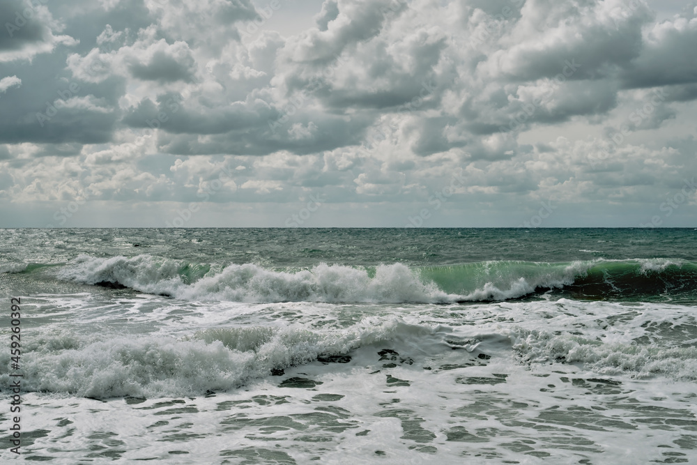 Running waves on the beach, sunny and windy summer day with cloudy skies, perfect surfing weather. Sea view