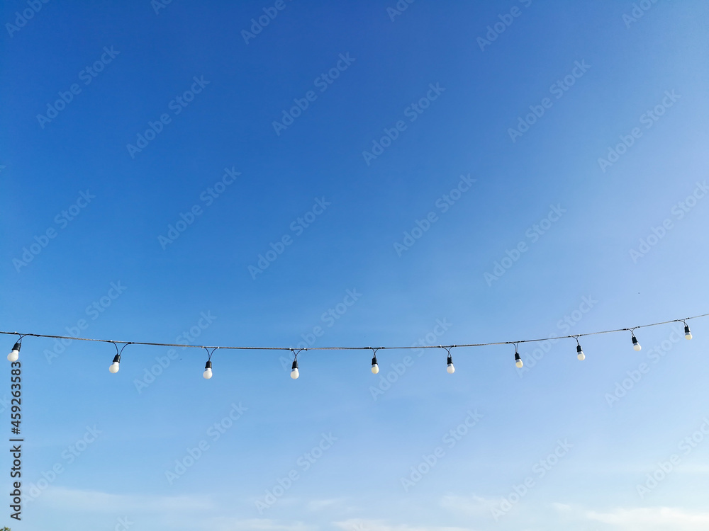 Beautiful clear sky with light bulbs hanging on a rope in park at Krabi Thailand and soft clouds make you feel and see the good weather in the morning of a new day. Ideas: the feeling of fresh weather Beautiful clear sky with light bulbs hanging on a rope in park at Krabi Thailand and soft clouds make you feel and see the good weather in the morning of a new day. Ideas: the feeling of fresh weather