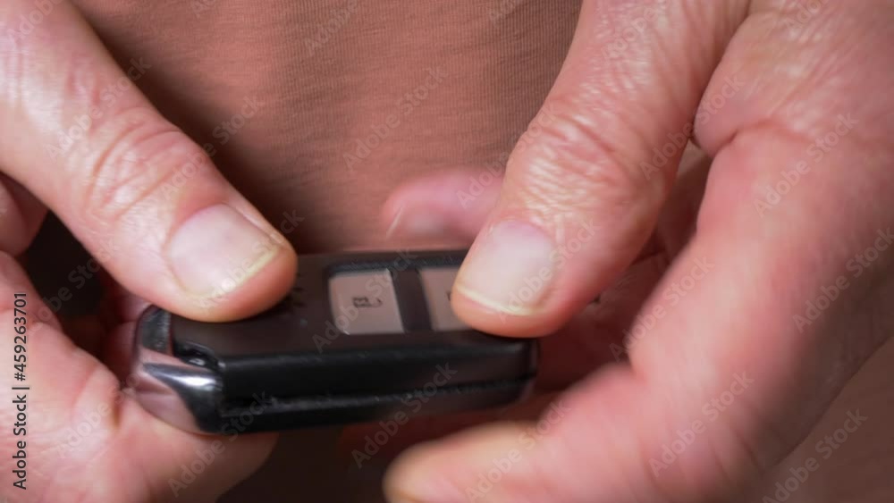 Closeup POV shot of a man’s hands putting a new button battery inside a vehicle keyless fob, then snapping the two open halves shut, ready to use. Closeup POV shot of a man’s hands putting a new button battery inside a vehicle keyless fob, then snapping the two open halves shut, ready to use.