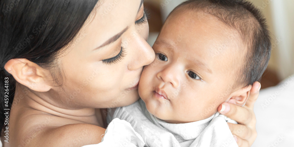 Portrait of enjoy happy love family asian mother playing with adorable little asian baby.Mom kiss with cute son moments good time in a white bedroom.Love of family concept Portrait of enjoy happy love family asian mother playing with adorable little asian baby.Mom kiss with cute son moments good time in a white bedroom.Love of family concept