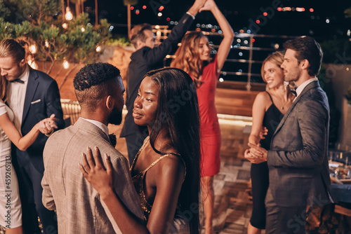 Beautiful young people dancing and smiling while spending time on luxury party
