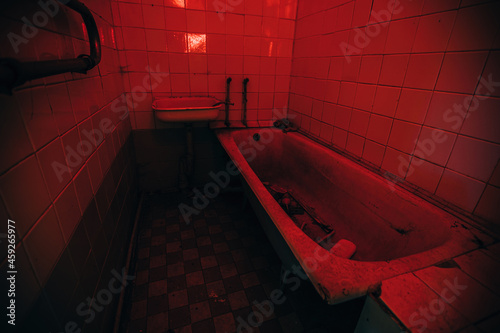 Creepy bath room in abandoned hospital. Red illuminated, horror concept photo