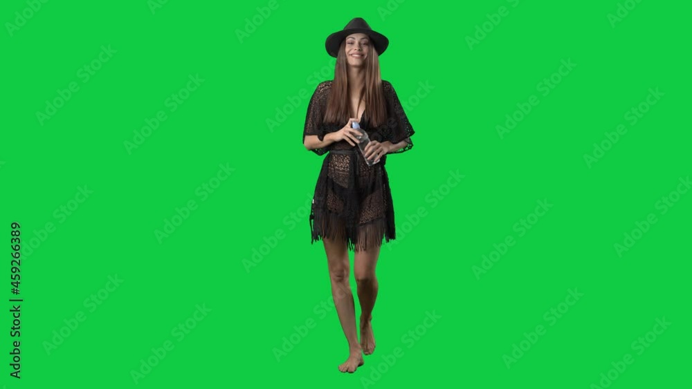 Happy woman in bikini and tunic walking barefoot drinking water in beachwear. Full body on green screen chroma key background Happy woman in bikini and tunic walking barefoot drinking water in beachwear. Full body on green screen chroma key background