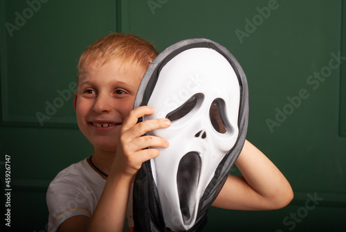Foto a little boy with a theatrical mask in his hands on Halloween depicts laughter m