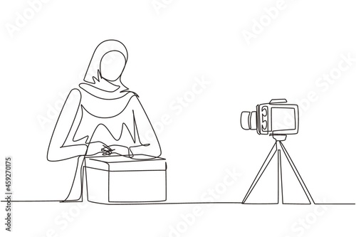Single one line drawing beauty Arabic female show unboxing received package in live at home. Woman vlogger unboxing product, recording review on camera. Continuous line draw design vector illustration