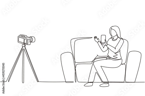 Single one line drawing female influencer filming video review smartphone on dslr camera at home. Blogger advertising tech product, streaming live. Continuous line draw design vector illustration