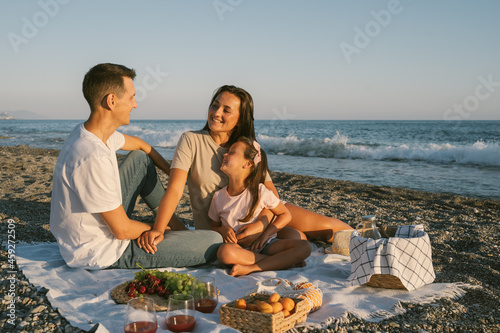 Summer family leisure picnic lunch with fruits by the seaside. Happy people eating healthy food on the spending time together outdoor.