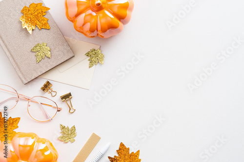 Autumn feminine desk table with pumpkins, glasses, notebook on white background. Cozy home workspace top view. Flat lay.