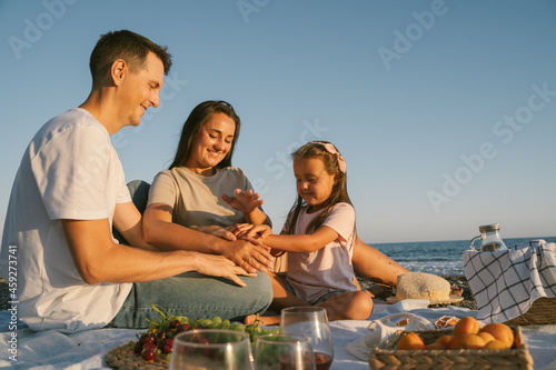 Summer family leisure picnic lunch with fruits by the seaside. Happy people eating healthy food on the spending time together outdoor.