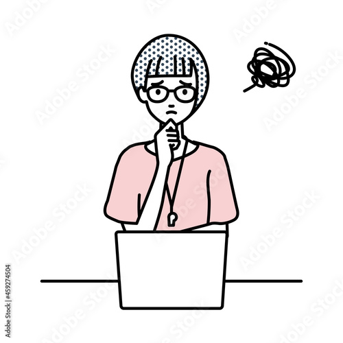 デスクで座ってPCを開いて困っている教師の女性